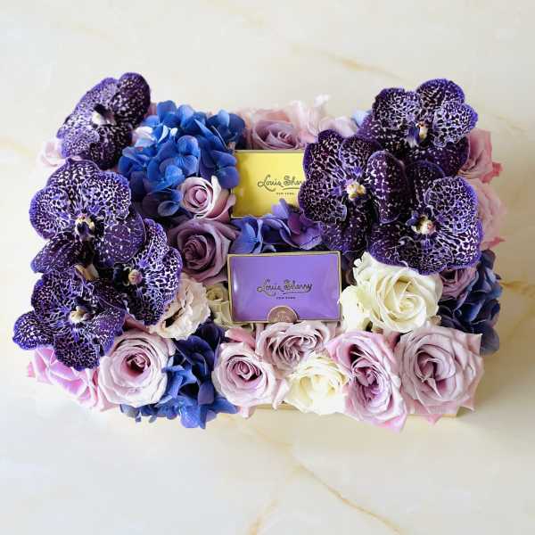 Box of purple orchids and pastel roses with two perfume boxes