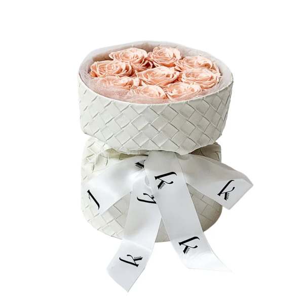Peach roses in a white woven hatbox with a ribbon bow