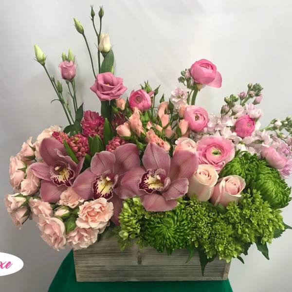 Pink and green mixed flower arrangement in a wooden box