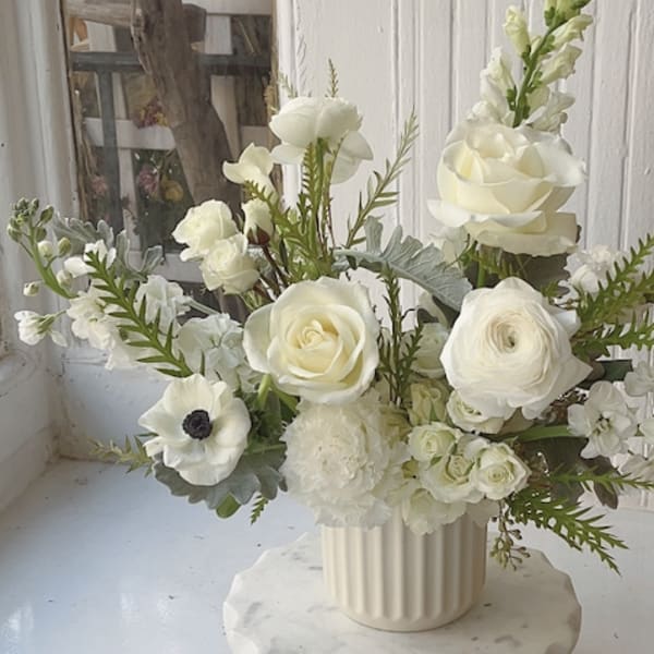 White floral arrangement in a ribbed cream vase