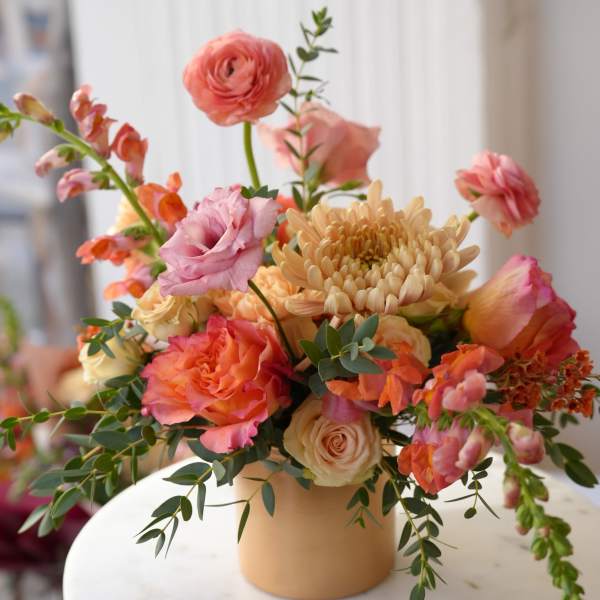Peach and pink mixed bouquet in a tan vase