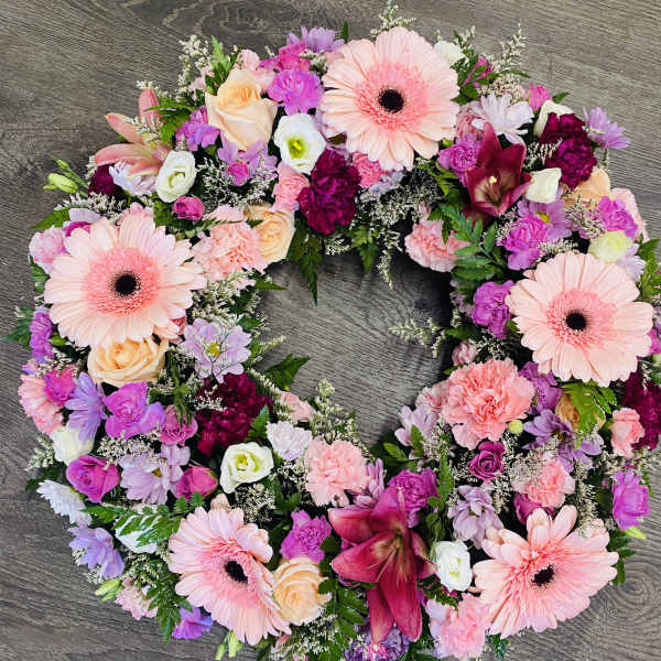 Circular floral wreath with pink gerberas, roses, and carnations