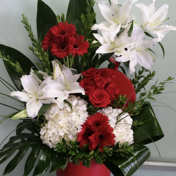 Red and white floral arrangement in a red container