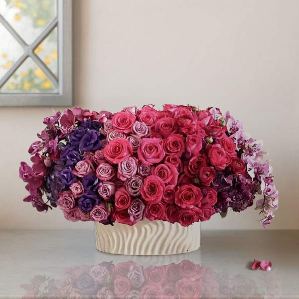 Pink and purple roses arranged in a low white vase