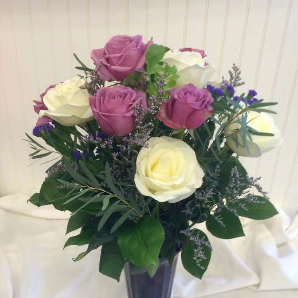 Pink and white roses arranged in a purple vase