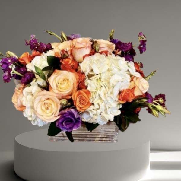 Mixed bouquet of peach, white, orange, and purple flowers in a wooden box