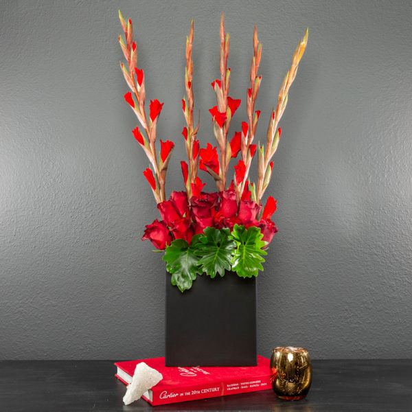 Red floral arrangement in a black rectangular vase with tall stems