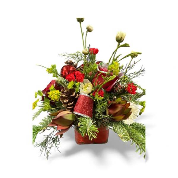 Holiday floral arrangement in a red square vase with pinecones and red accents