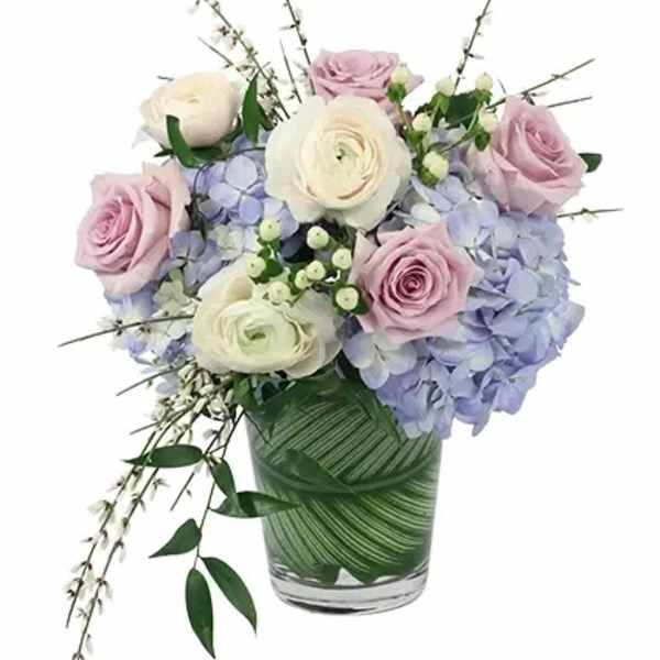 Bouquet of pink and white roses with blue hydrangeas in a glass vase