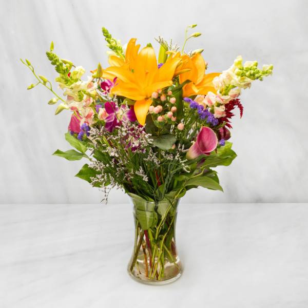 Mixed bouquet with yellow lilies and pink calla lilies in a clear glass vase