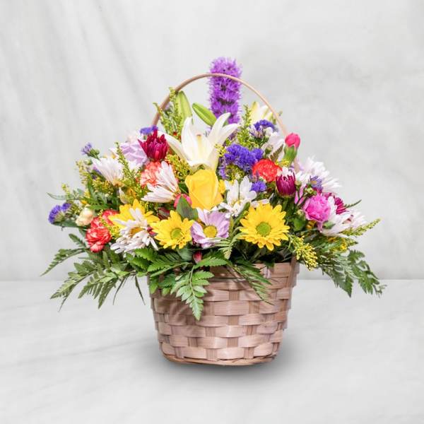 Mixed flower basket with daisies, lilies, and roses in a woven basket