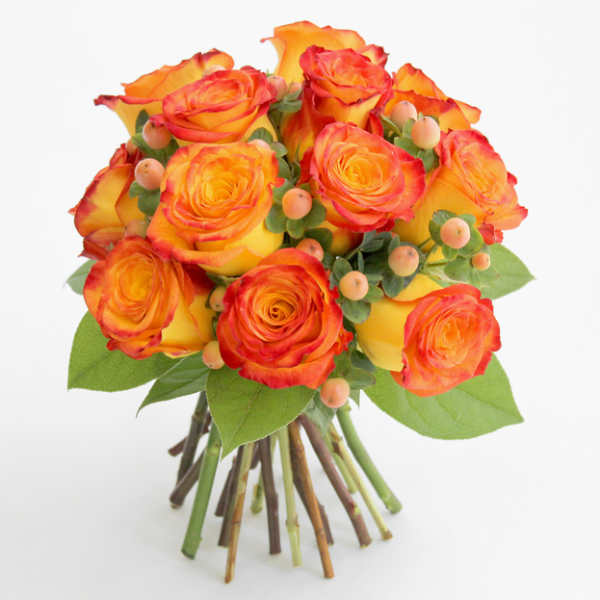 Bouquet of orange and yellow roses with small berry accents