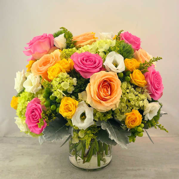 Bouquet of pink, peach, yellow, and white roses in a glass vase