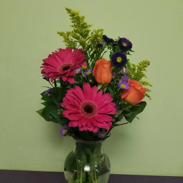 Pink gerbera daisies and orange roses in a glass vase