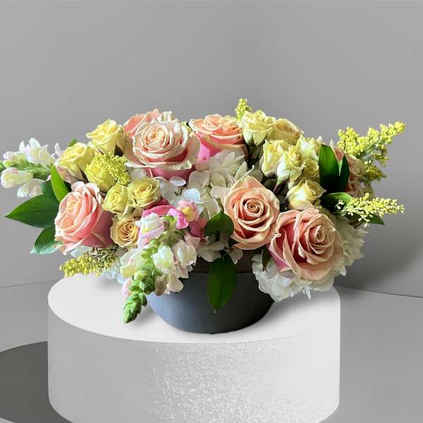 Bouquet of peach and yellow roses in a black container