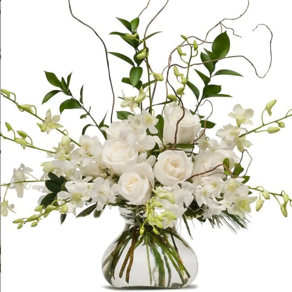 White roses and orchids in a clear glass vase