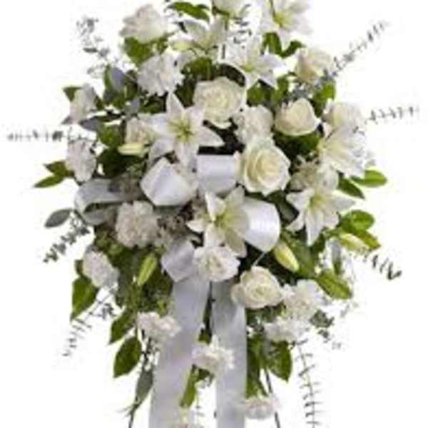 White funeral spray with lilies, roses, and ribbon