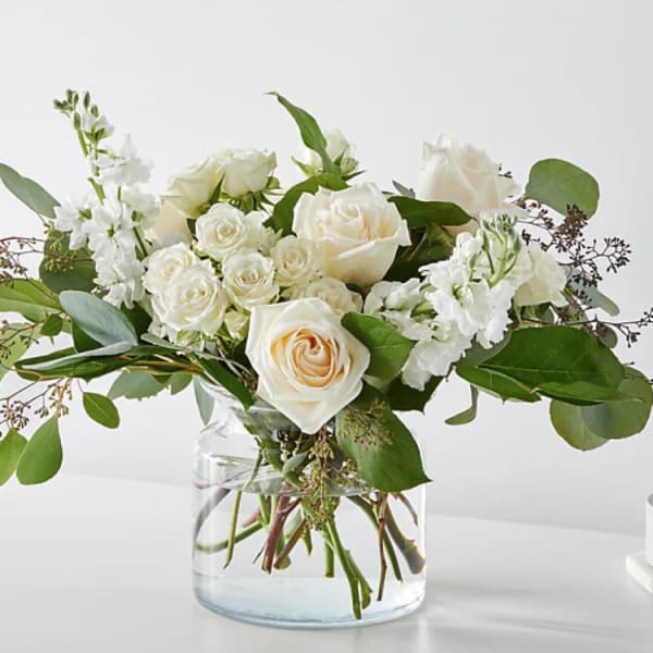 White roses and stock in a clear glass vase