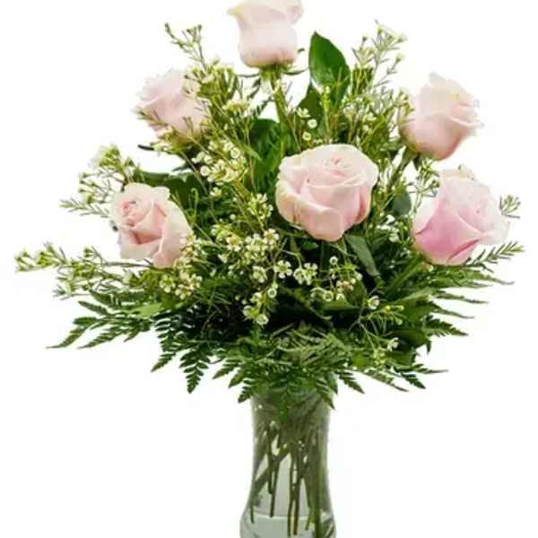 Pink roses in a clear glass vase with greenery