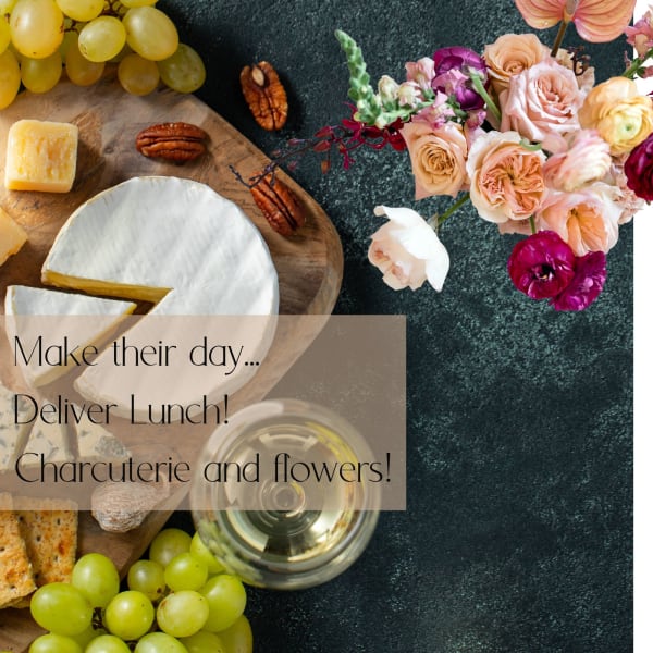 Charcuterie board with cheese, grapes, nuts, wine, and a flower bouquet
