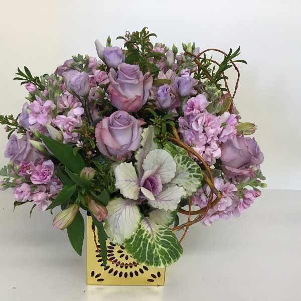 Lavender roses and pink flowers arranged in a yellow box
