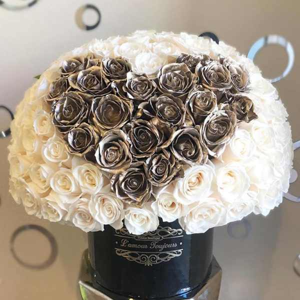 Heart-shaped rose arrangement in a black hatbox on a mirrored stand
