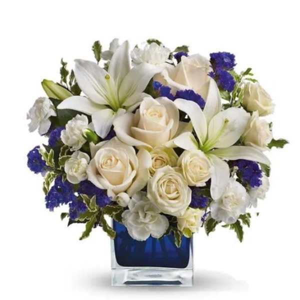 White lilies and cream roses arranged in a blue glass vase