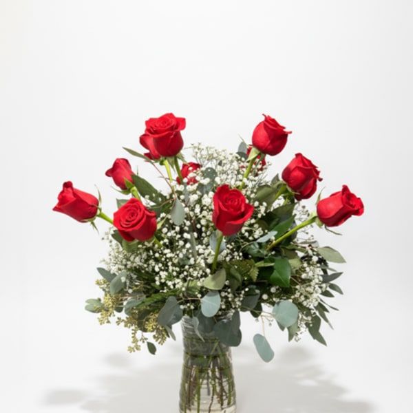 Red roses arranged in a clear glass vase with white filler flowers