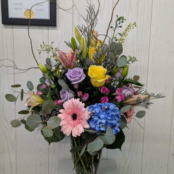 Mixed bouquet in a glass vase with roses, lilies, gerbera daisies, and hydrangea