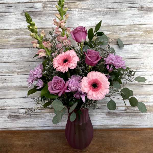 Pink and purple mixed flower arrangement in a burgundy vase