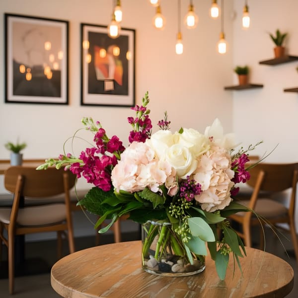 Pink and white floral arrangement in a clear glass vase on a table