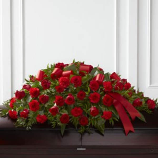 Red rose casket spray with a red ribbon on a dark casket