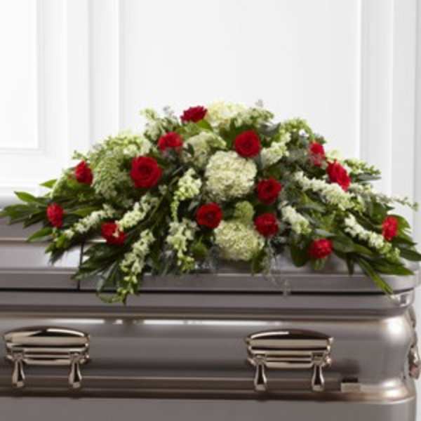 Red roses and white flowers arranged on a silver casket