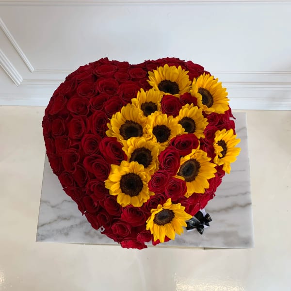 Heart-shaped arrangement of red roses with yellow sunflowers