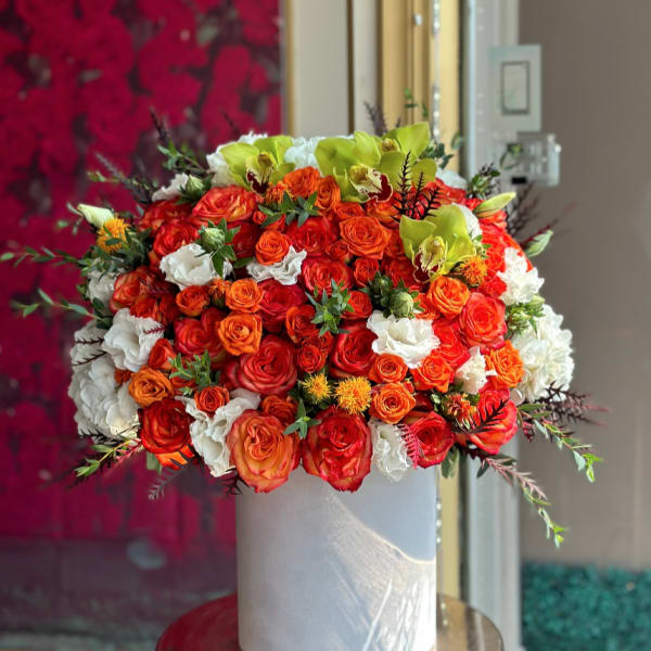 Large bouquet of orange, red, white, and green flowers in a white box