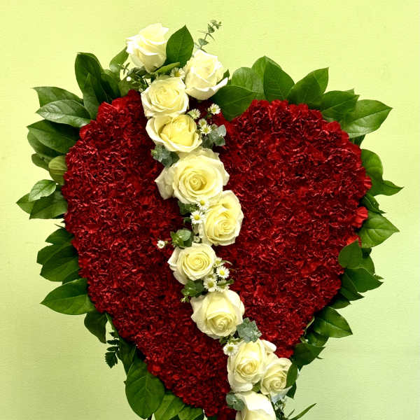 Heart-shaped red floral tribute with white roses on a stand