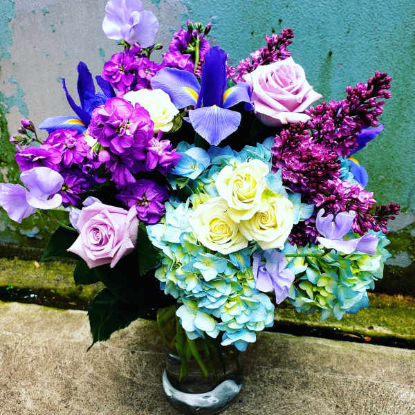 Bouquet of roses, hydrangeas, irises, and lilacs in a glass vase