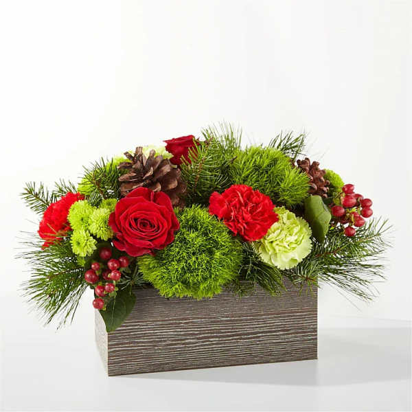Red roses and carnations in a wooden box with pinecones and greenery