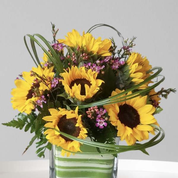Sunflower bouquet in a square glass vase with pink filler flowers