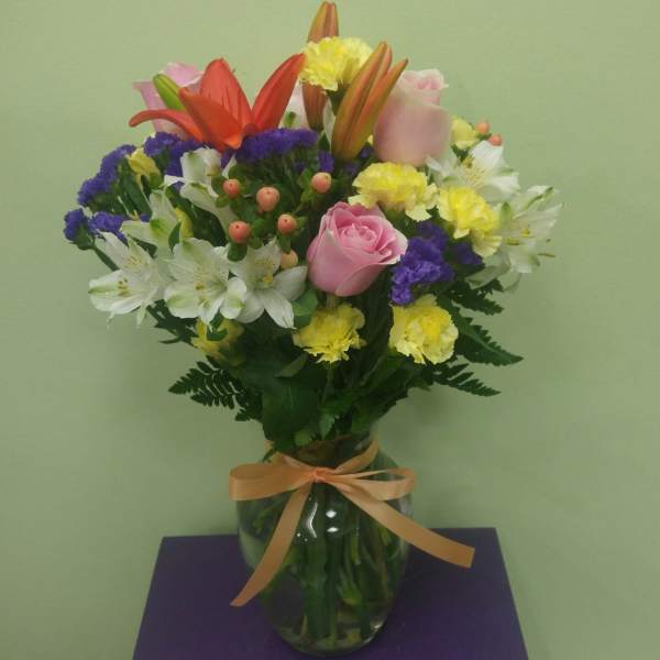 Mixed bouquet of lilies, roses, and carnations in a glass vase