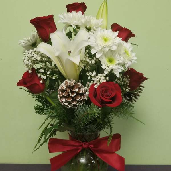 Red roses and white lilies in a glass vase with a red bow