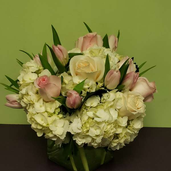 Pink and white roses with hydrangeas in a glass vase