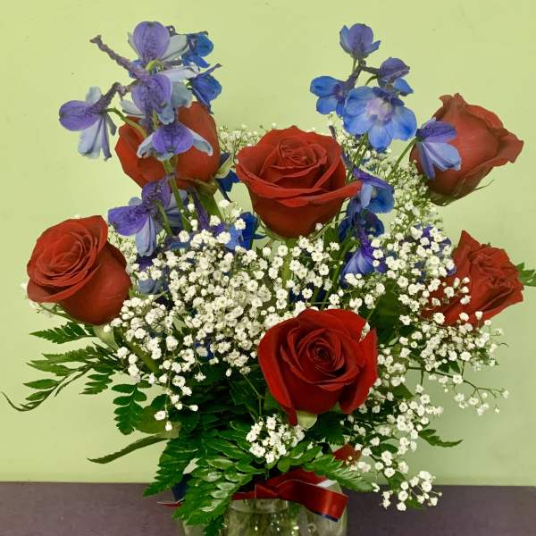 Red roses and blue-purple flowers in a glass vase