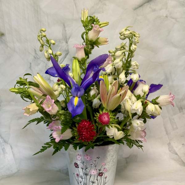 Mixed bouquet with purple irises and pink-white blooms in a decorative metal bucket