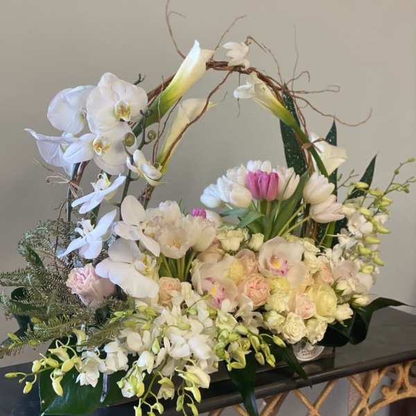Large floral basket with white orchids, tulips, and pale roses