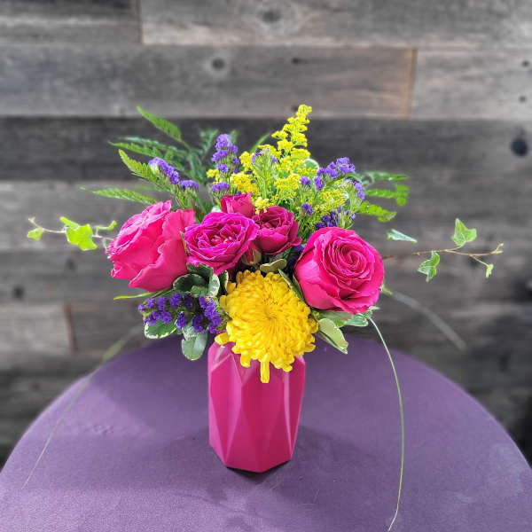 Pink roses and a yellow chrysanthemum in a pink vase