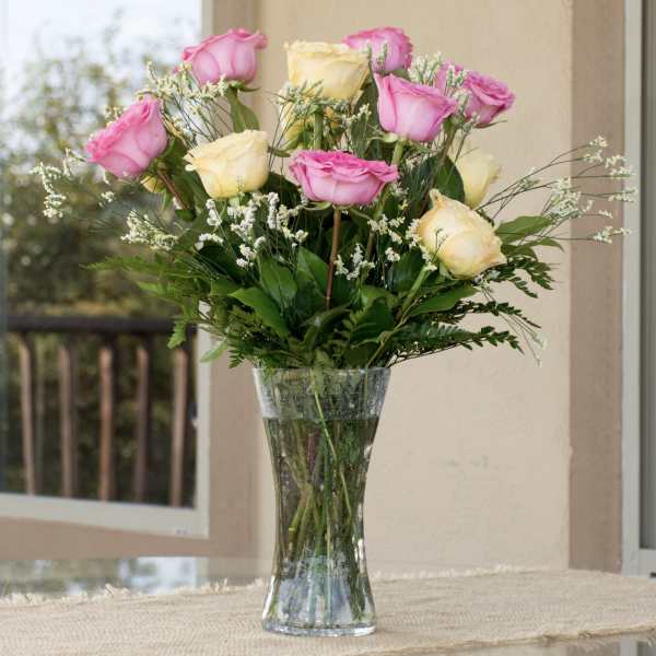 Pink and cream roses arranged in a clear glass vase