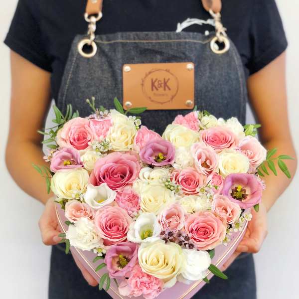 Heart-shaped box filled with pink and cream roses and other blooms