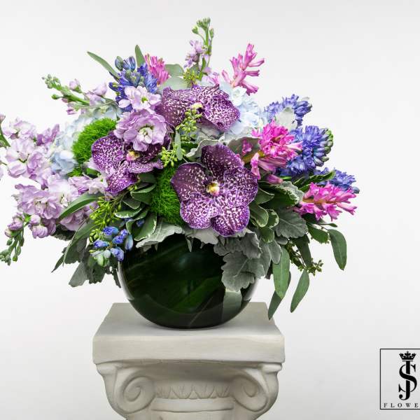 Mixed purple and blue flowers arranged in a dark glass vase