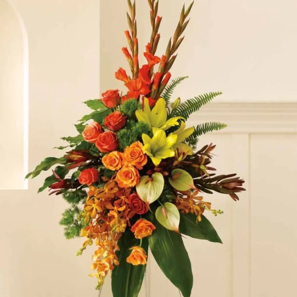 Tall floral arrangement with orange and yellow blooms on a stand